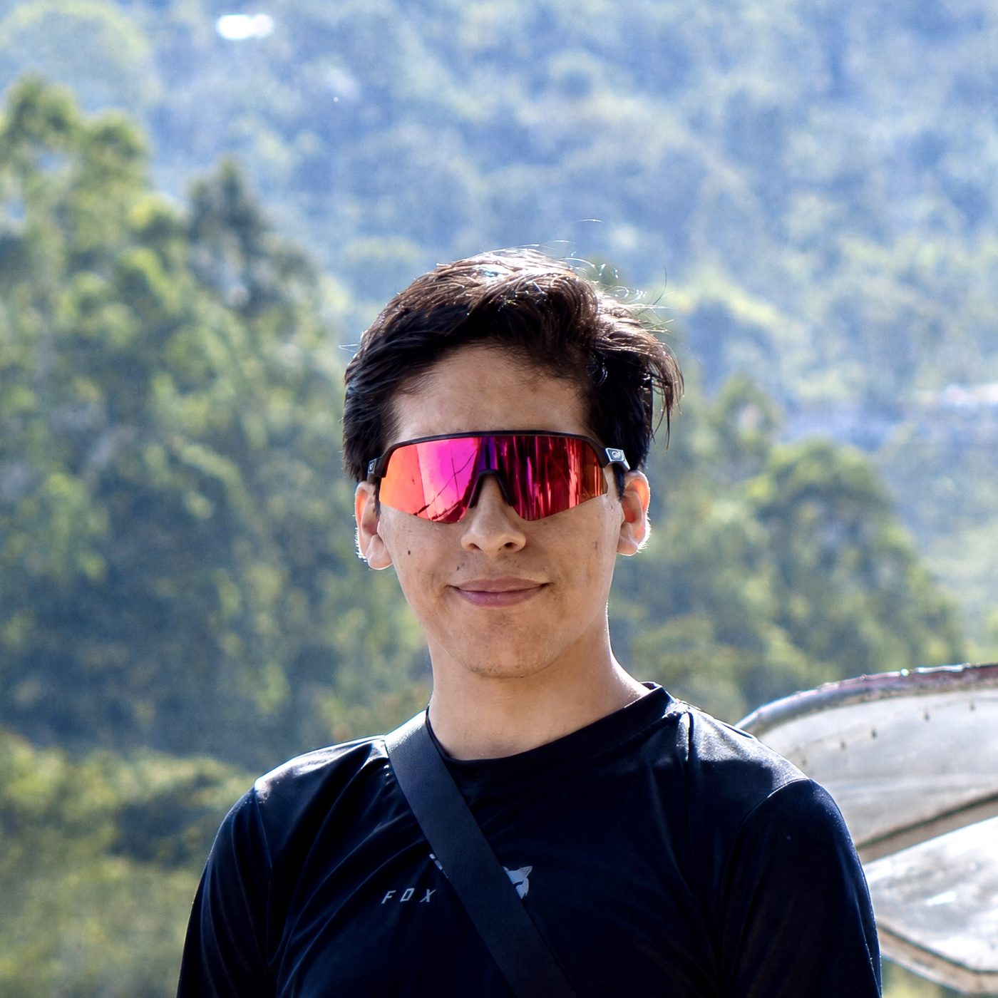 Retrato de Jonel Ralf con lentes de sol, fondo de bosque.